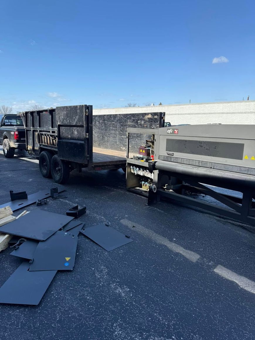 Overturned flatbed trailer on highway shoulder with debris scattered across the road under a clear blue sky