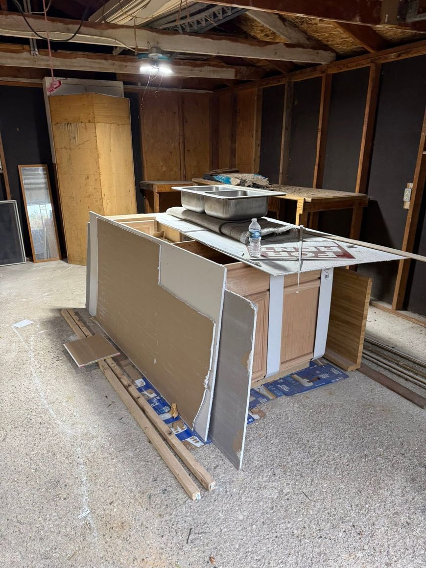 Partially built room with drywall panels, plywood boards, and construction materials in an unfinished basement