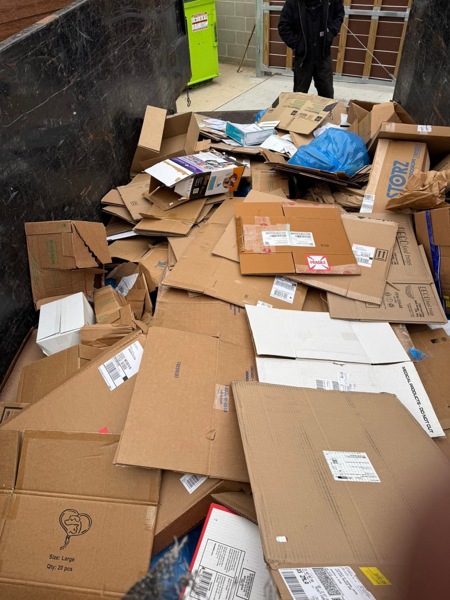 Pile of flattened cardboard boxes and packing debris scattered on the floor in a narrow indoor corridor.