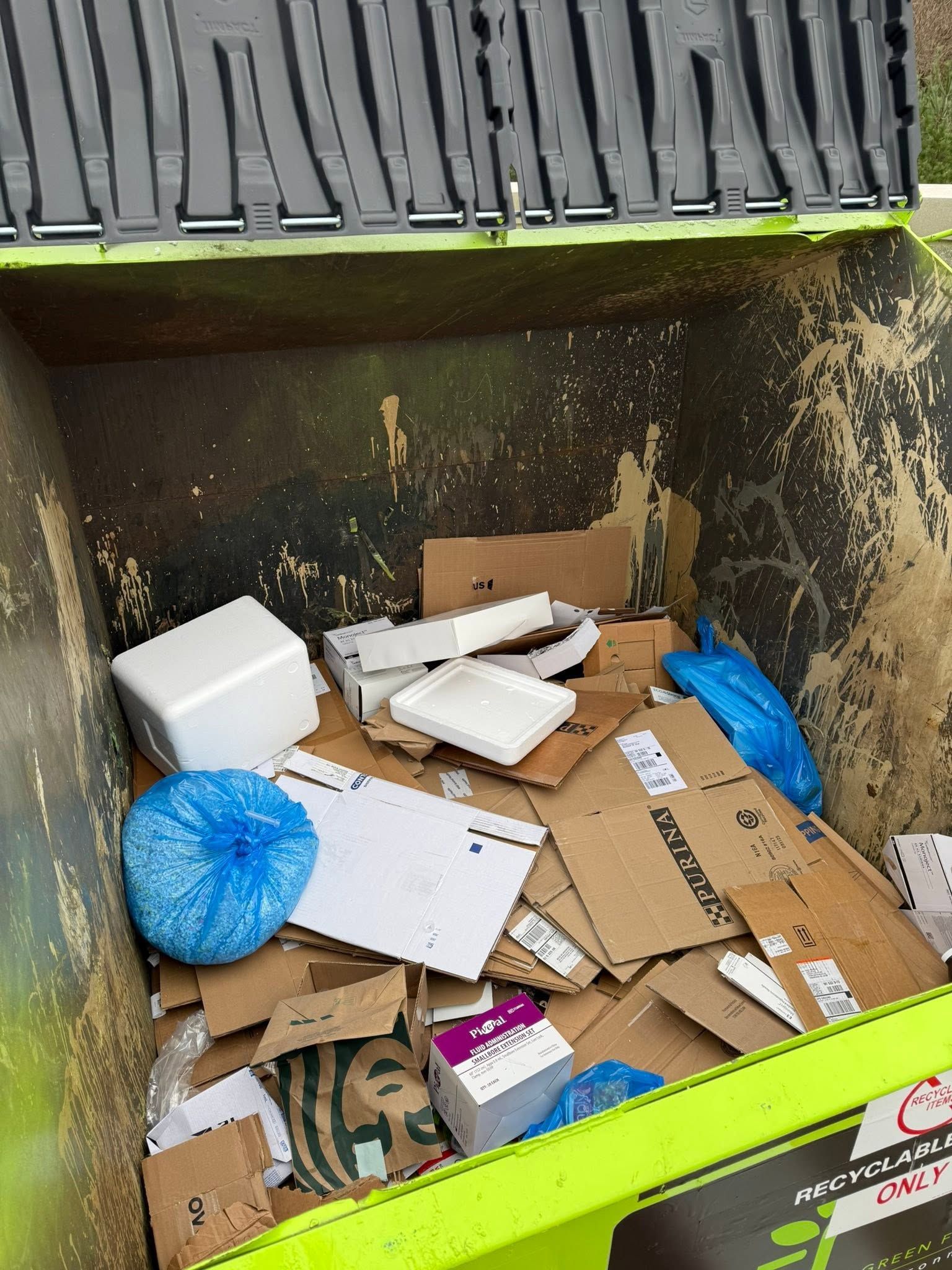 Trash bin filled with cardboard, foam packing, and a blue bag