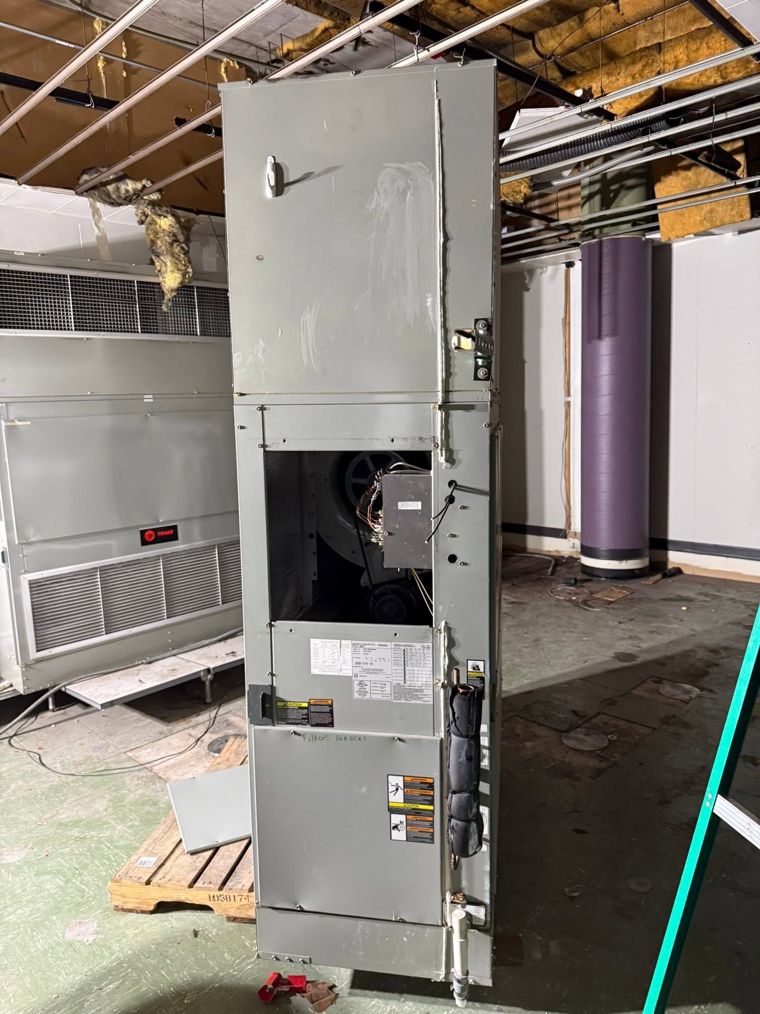 Tall gray HVAC unit in a mechanical room, with panels open and visible internal components.