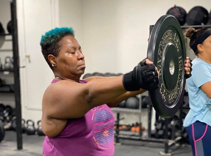 A woman is holding a barbell in her hand in a gym. A woman is holding a barbell in her hand in a gym.