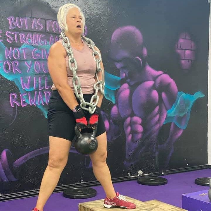 A woman wearing a chain around her neck is holding a kettlebell A woman wearing a chain around her neck is holding a kettlebell