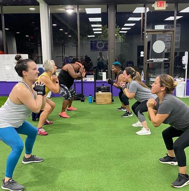 A group of people are squatting in a gym. A group of people are squatting in a gym.