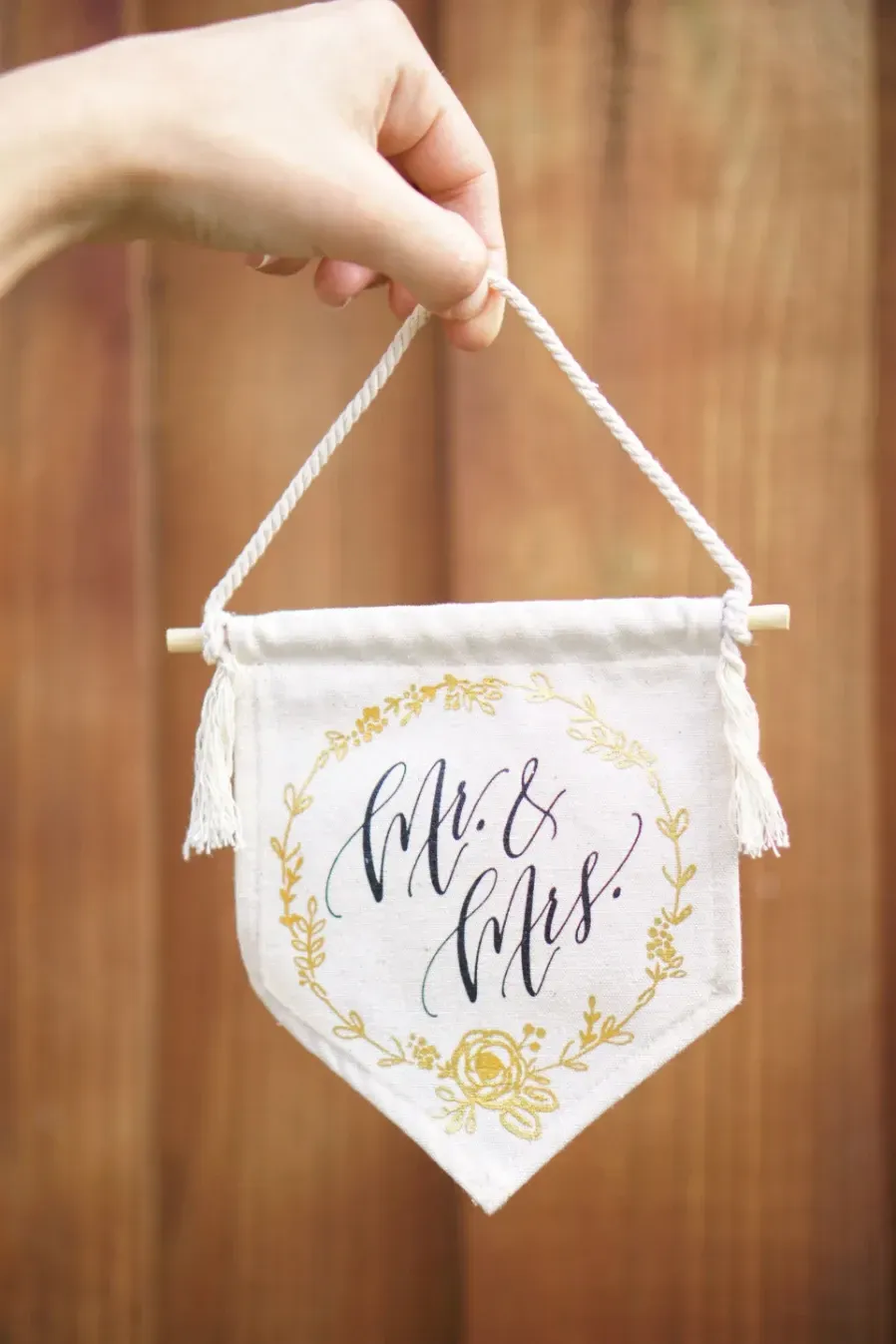 A white fabric wedding banner with elegant black cursive text reading 'Mr. and Mrs. Newlyweds'