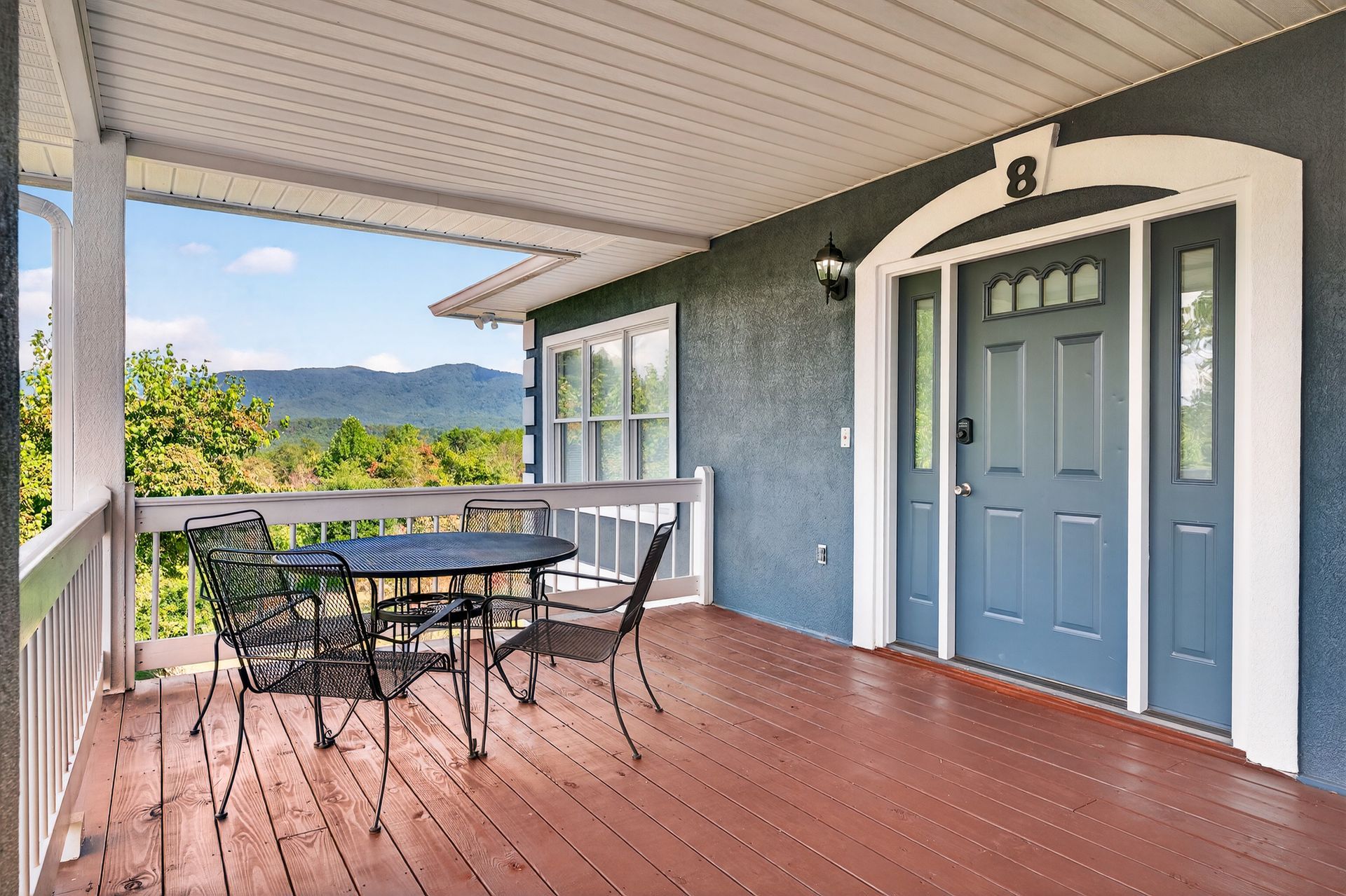 Covered porch with table and chairs, overlooking a scenic mountain view. The entrance is marked with number 8.