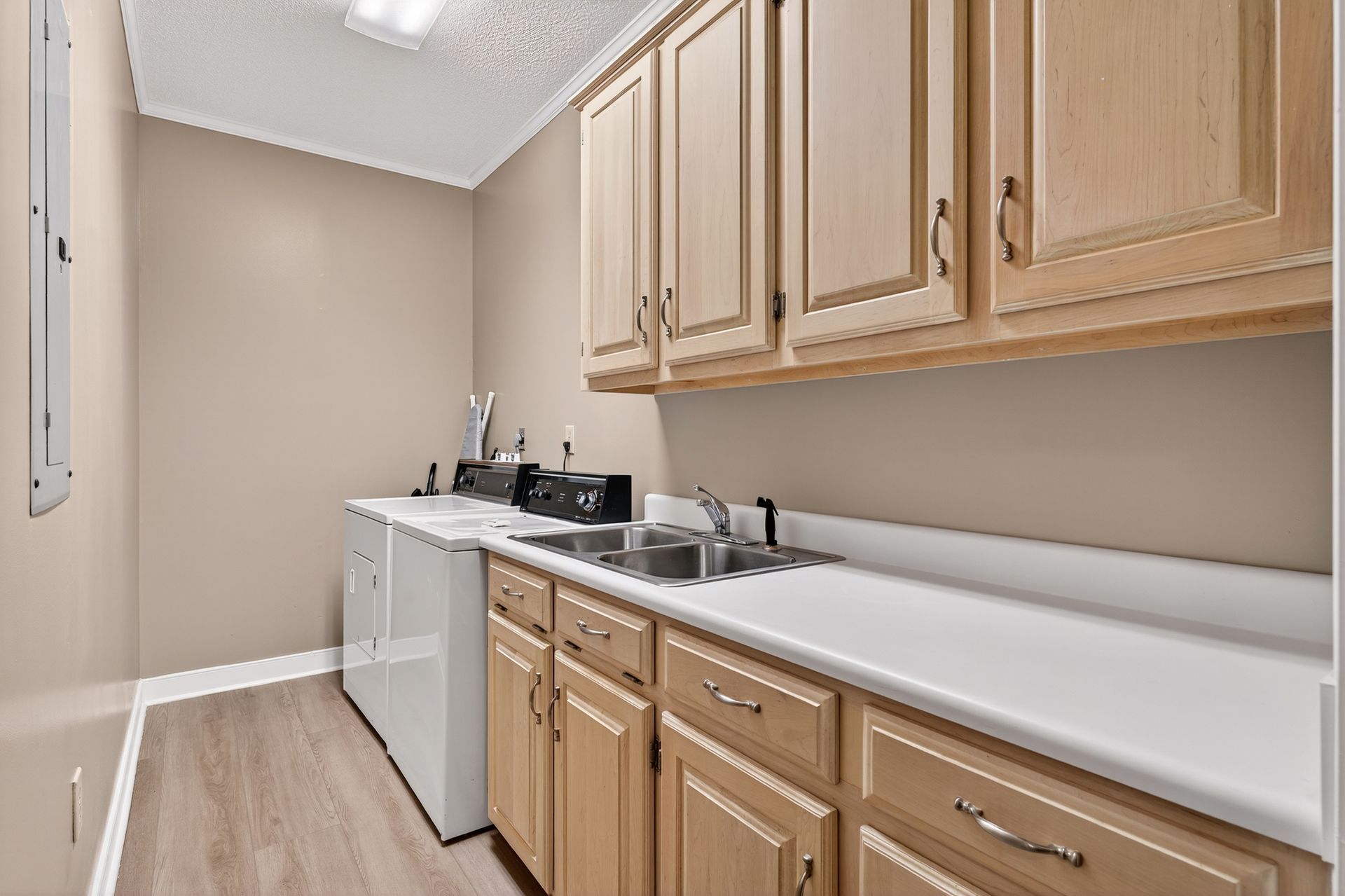 Laundry room with light wood cabinets, white countertops, and a washing machine.