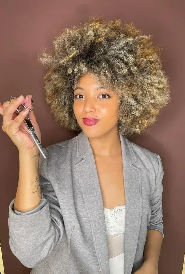 Uma mulher com cabelos cacheados está segurando uma caneta na mão.