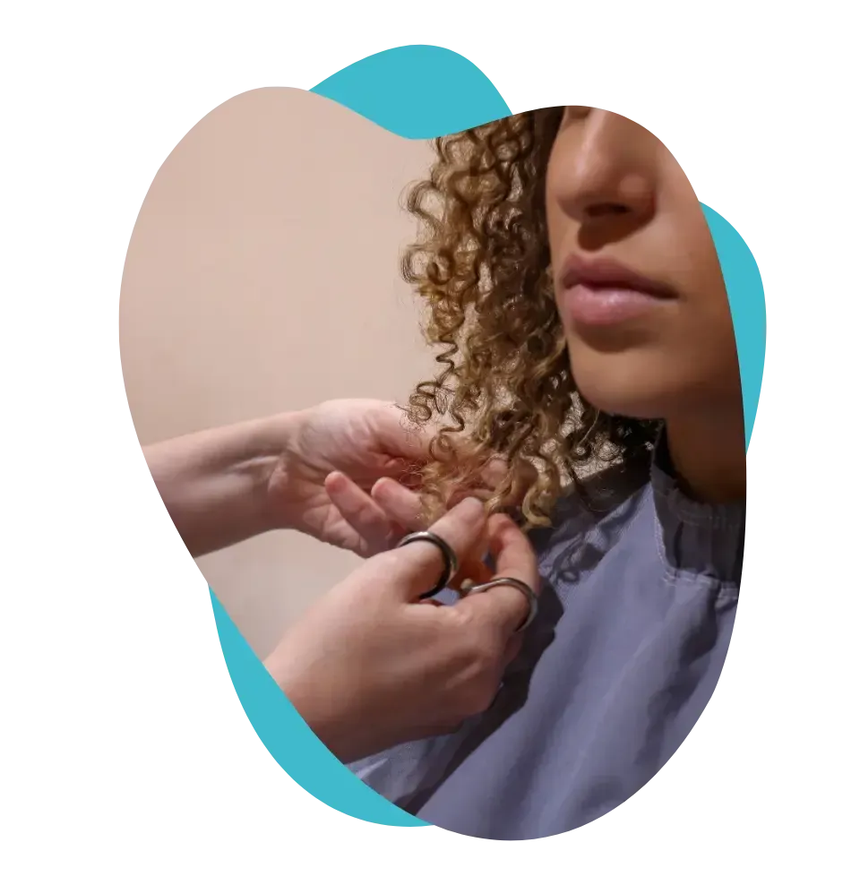 Uma mulher de cabelos cacheados está sendo penteada por um cabeleireiro.