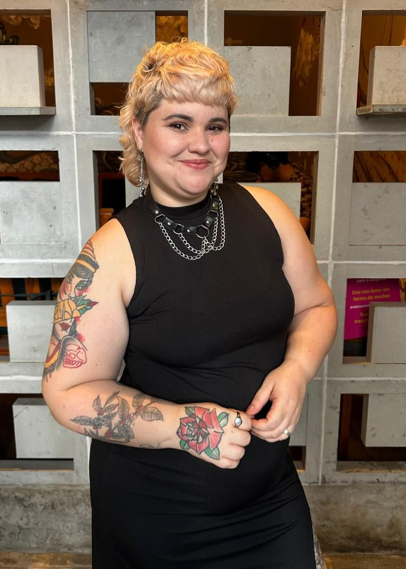 Uma mulher está vestindo um top verde e jeans azul.