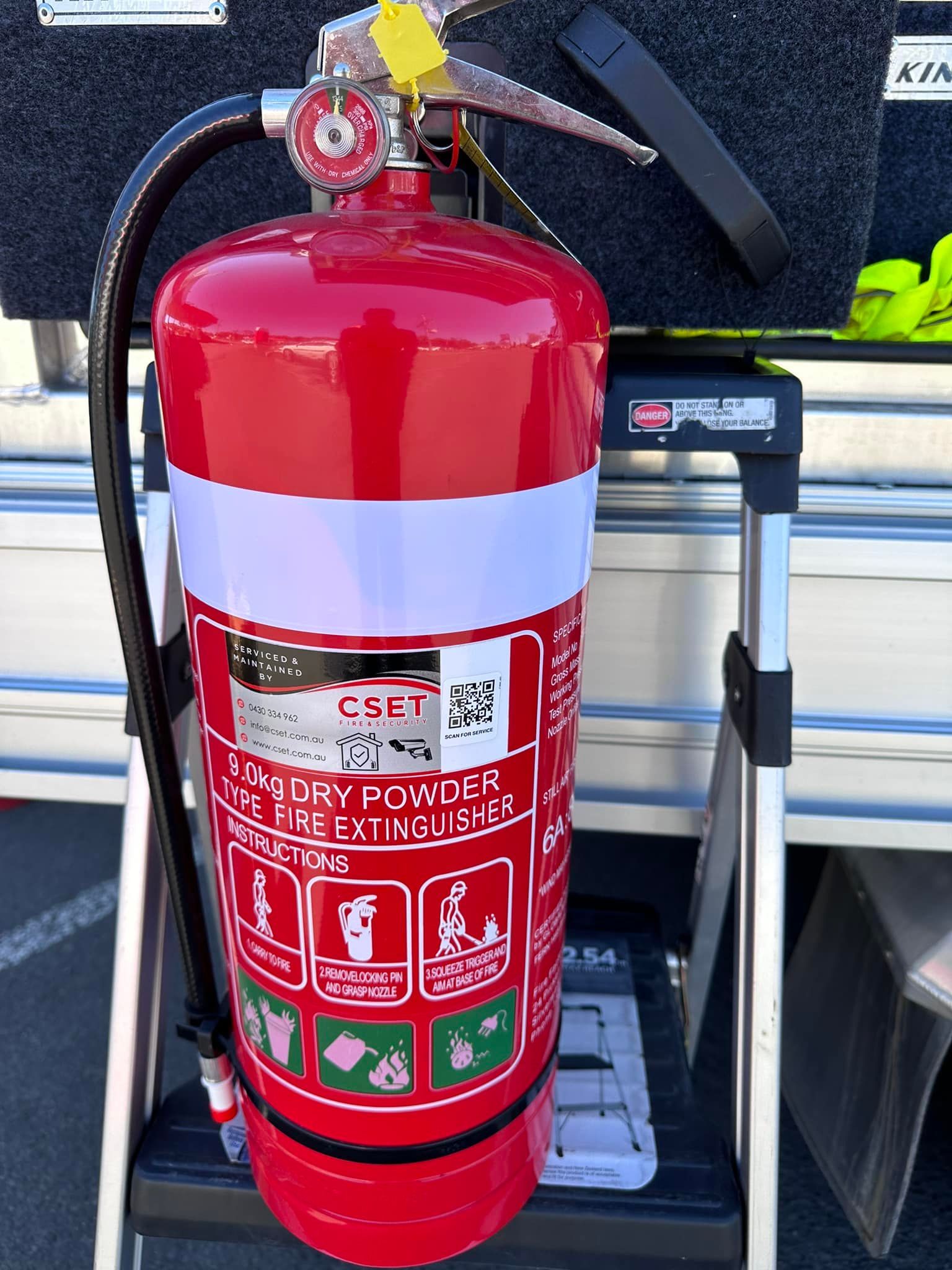 Red Fire Extinguisher Mounted Outdoors Against a Vehicle — CSET Group Fire & Security in Central Coast, NSW