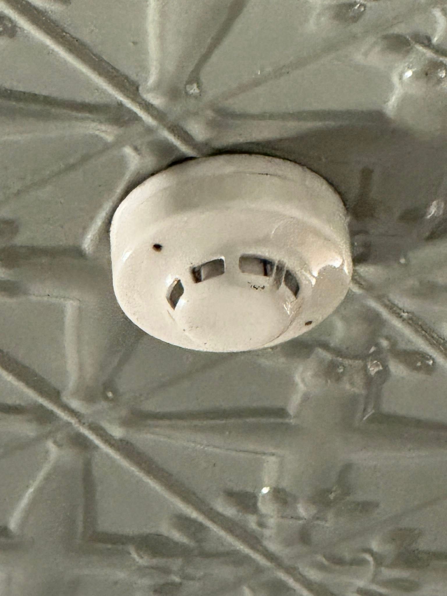 White Smoke Detector Mounted on a Patterned Ceiling — CSET Group Fire & Security in Lake Macquarie, NSW