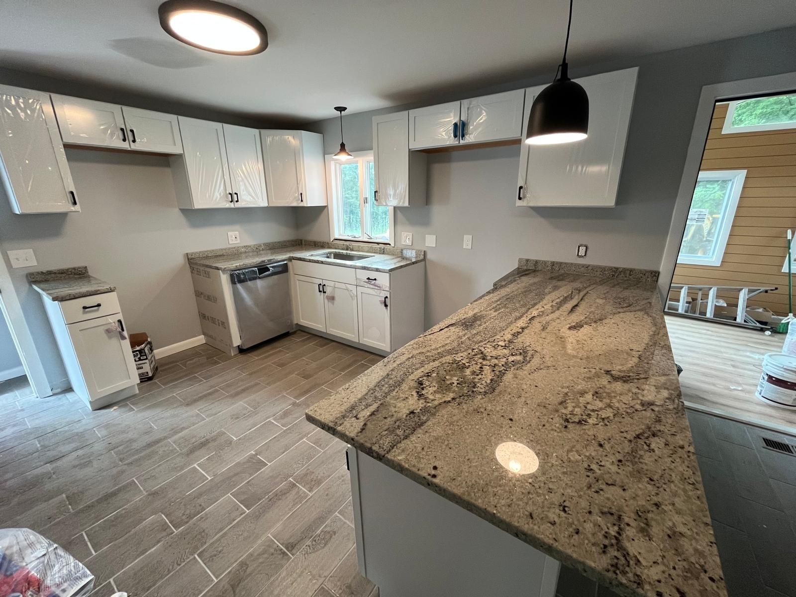 Newly remodeled kitchen with gray walls, white cabinets, granite countertops, and tiled floor.