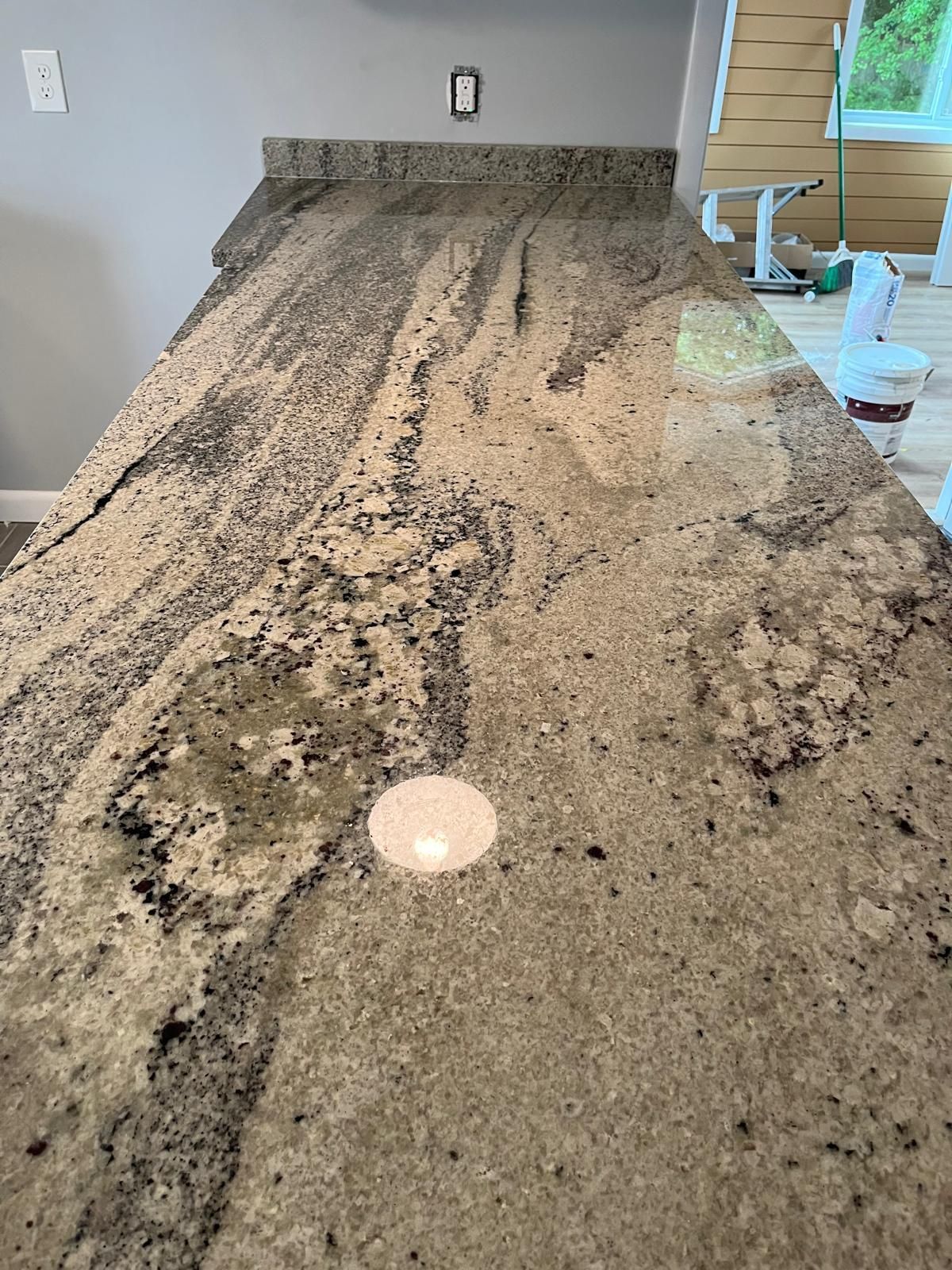 Granite countertop with swirling patterns in tan, black, and gray, in a kitchen setting.