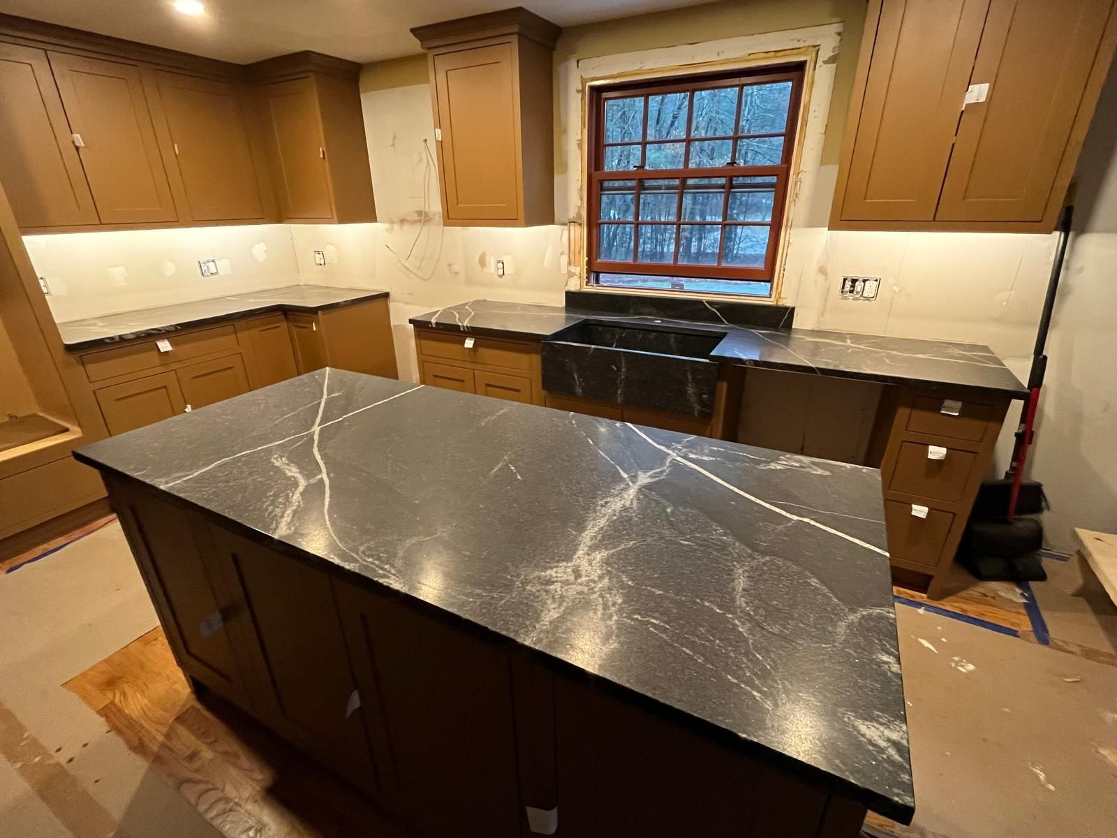 Kitchen with dark countertops, brown cabinets, and a window.