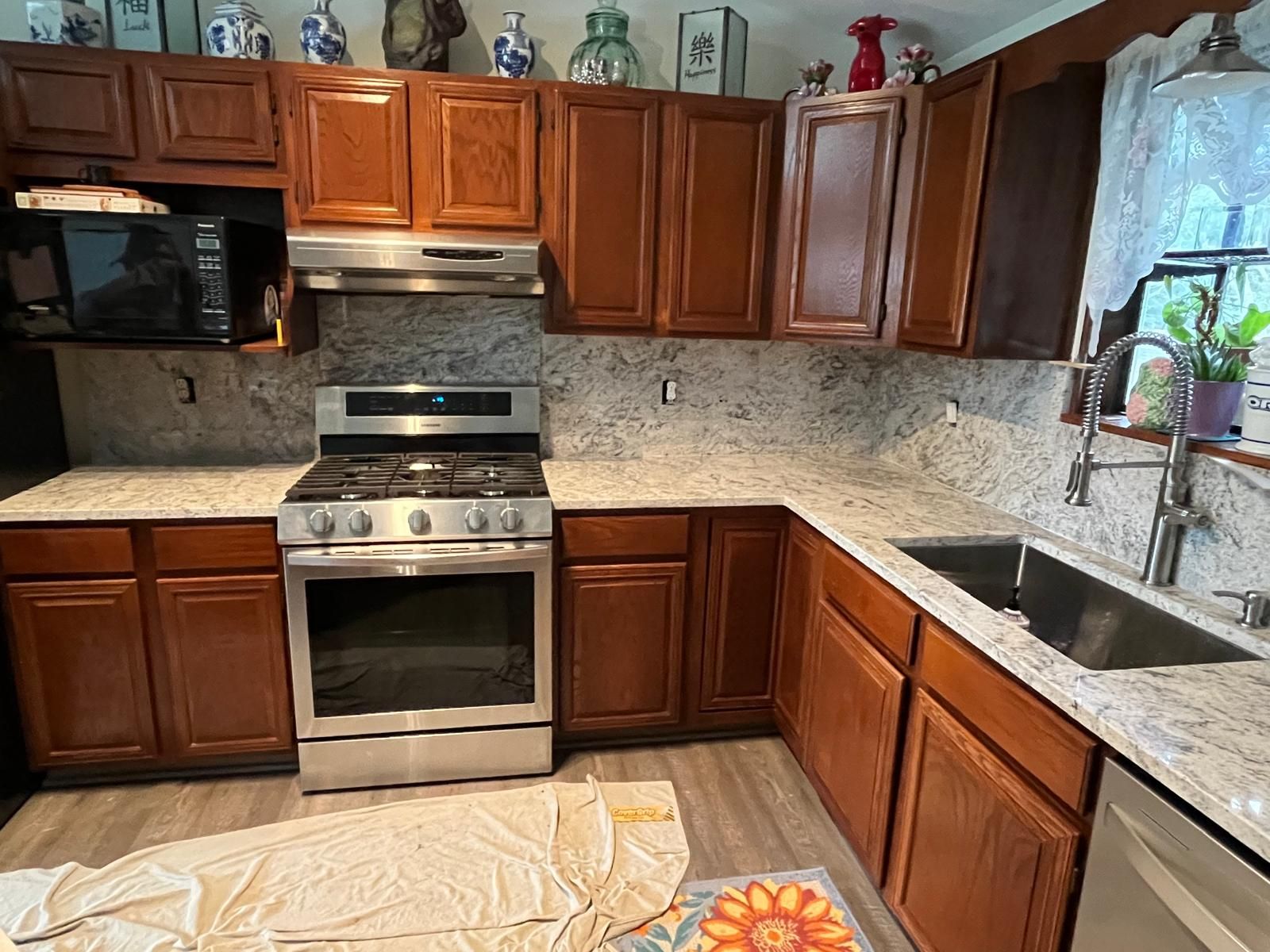 Kitchen with dark brown cabinets, stainless steel appliances, and light granite countertops.