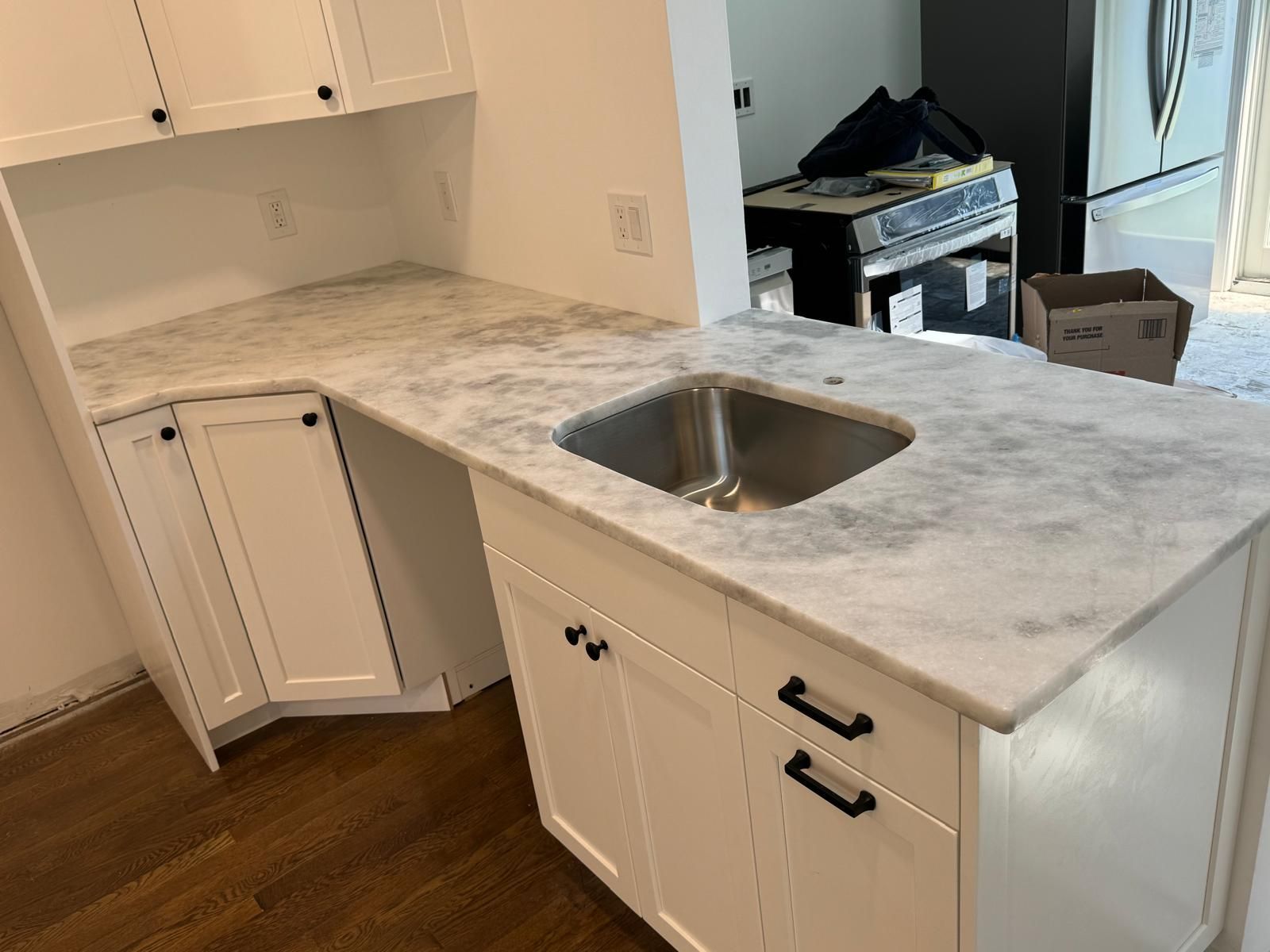 White kitchen cabinets and marble countertops with a sink.