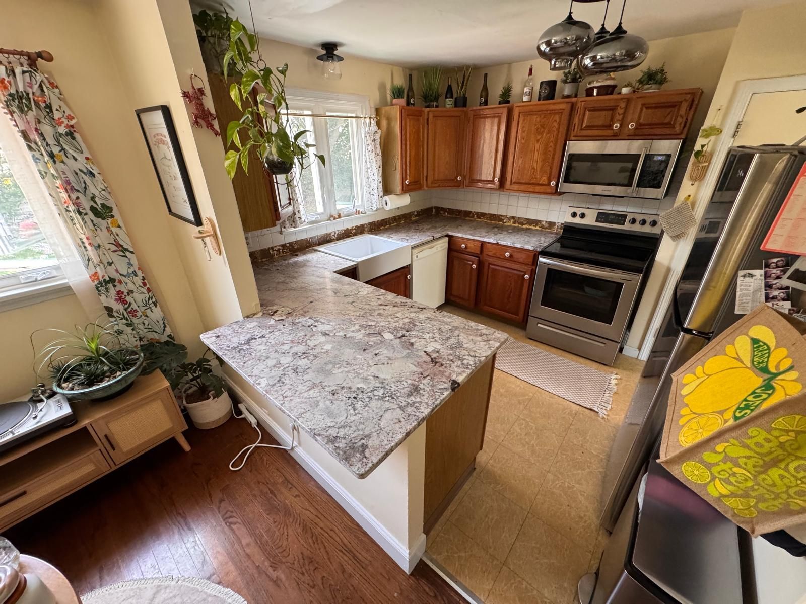 Kitchen with wooden cabinets, stainless steel appliances, and a central island with a speckled countertop.