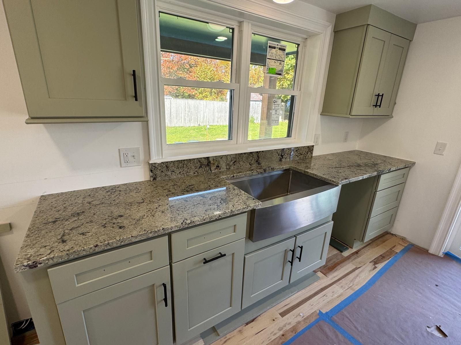 Kitchen remodel: sage green cabinets, granite countertop, stainless steel sink.