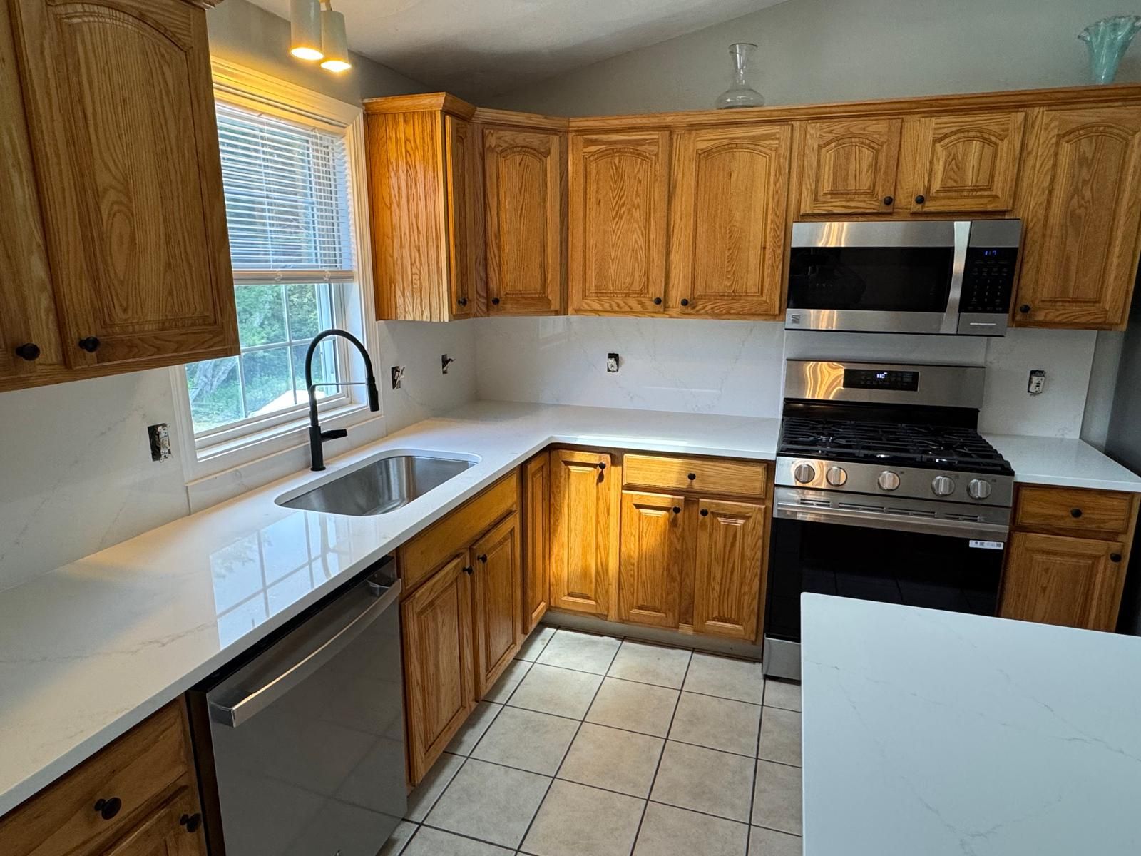 Kitchen with oak cabinets, white countertops, and stainless steel appliances.