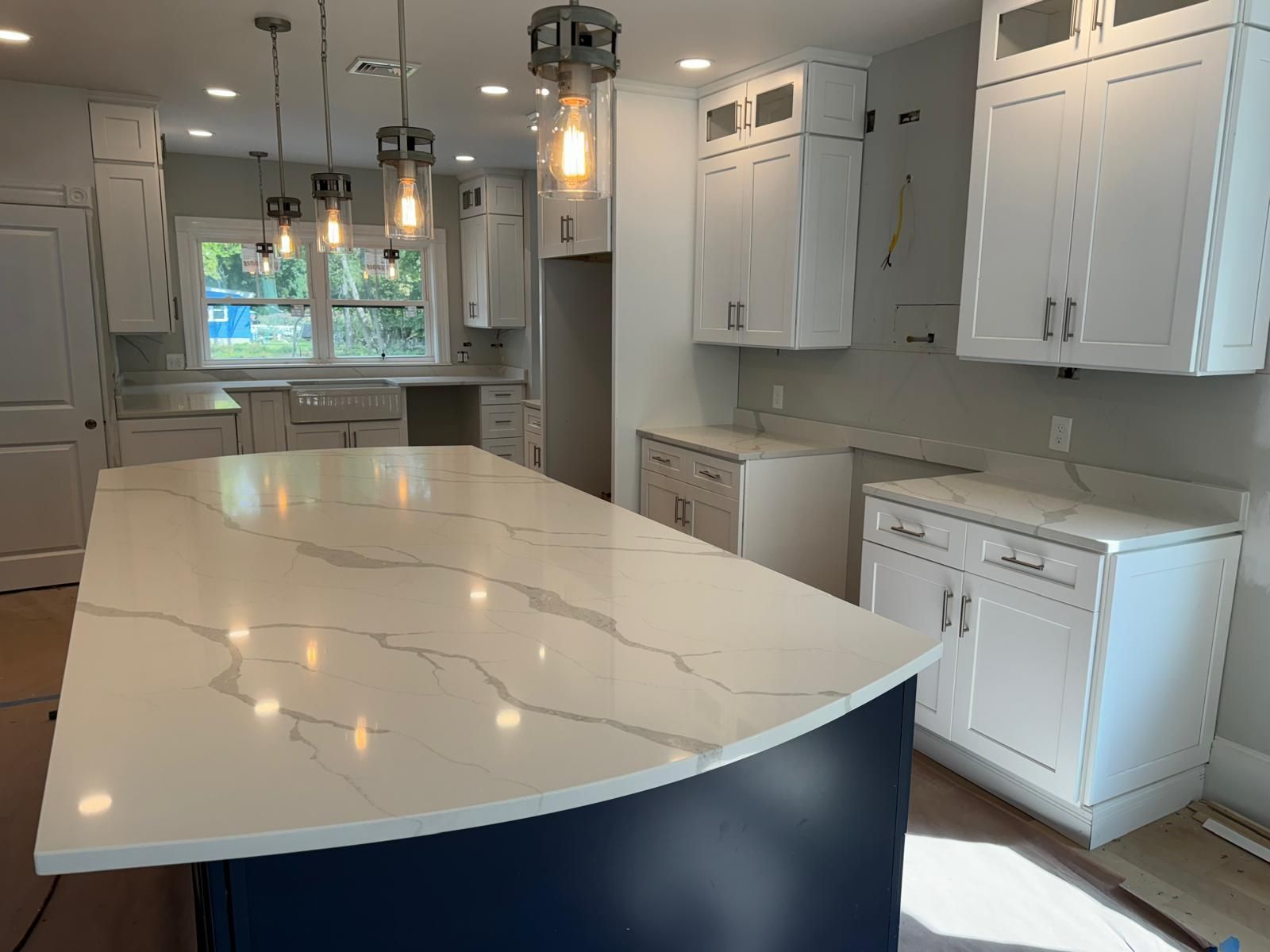 Modern white kitchen with a blue island and marble countertop.