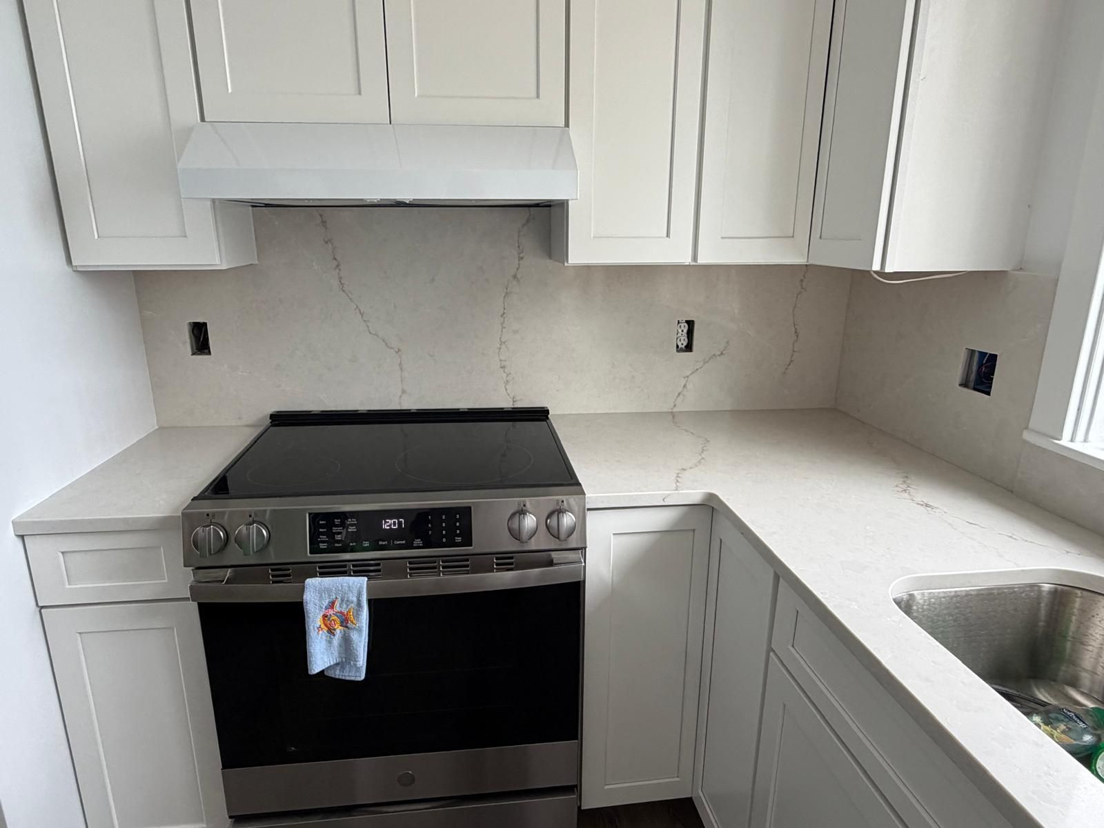 Kitchen with white cabinets, light countertops, and a stainless steel stove.
