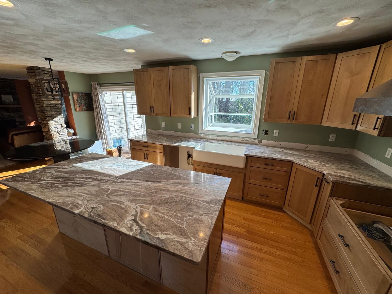 Kitchen with light wood cabinets, granite countertops, and an island. Natural light floods the space.