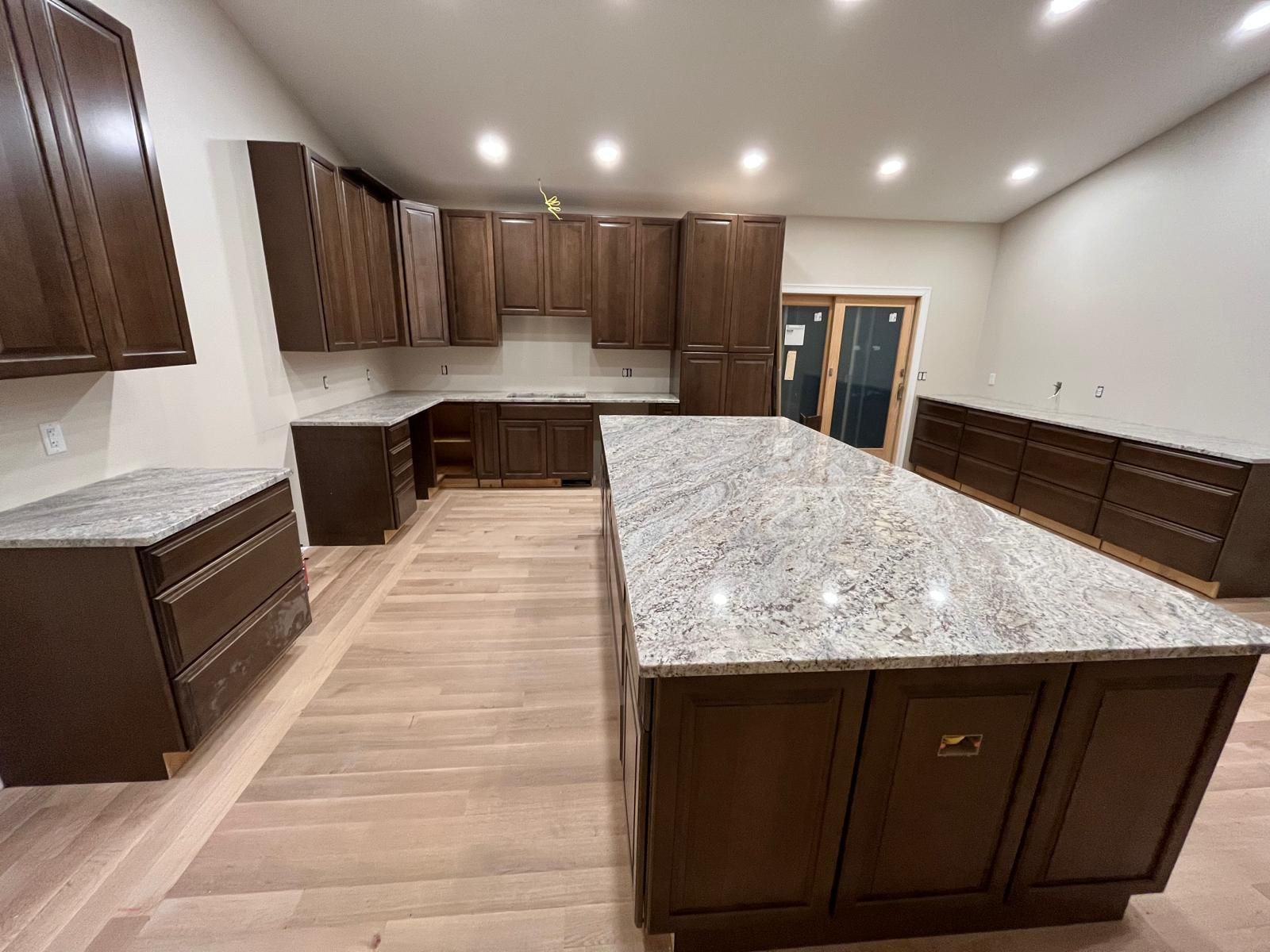 Brown kitchen cabinets with light granite countertops and a large island.