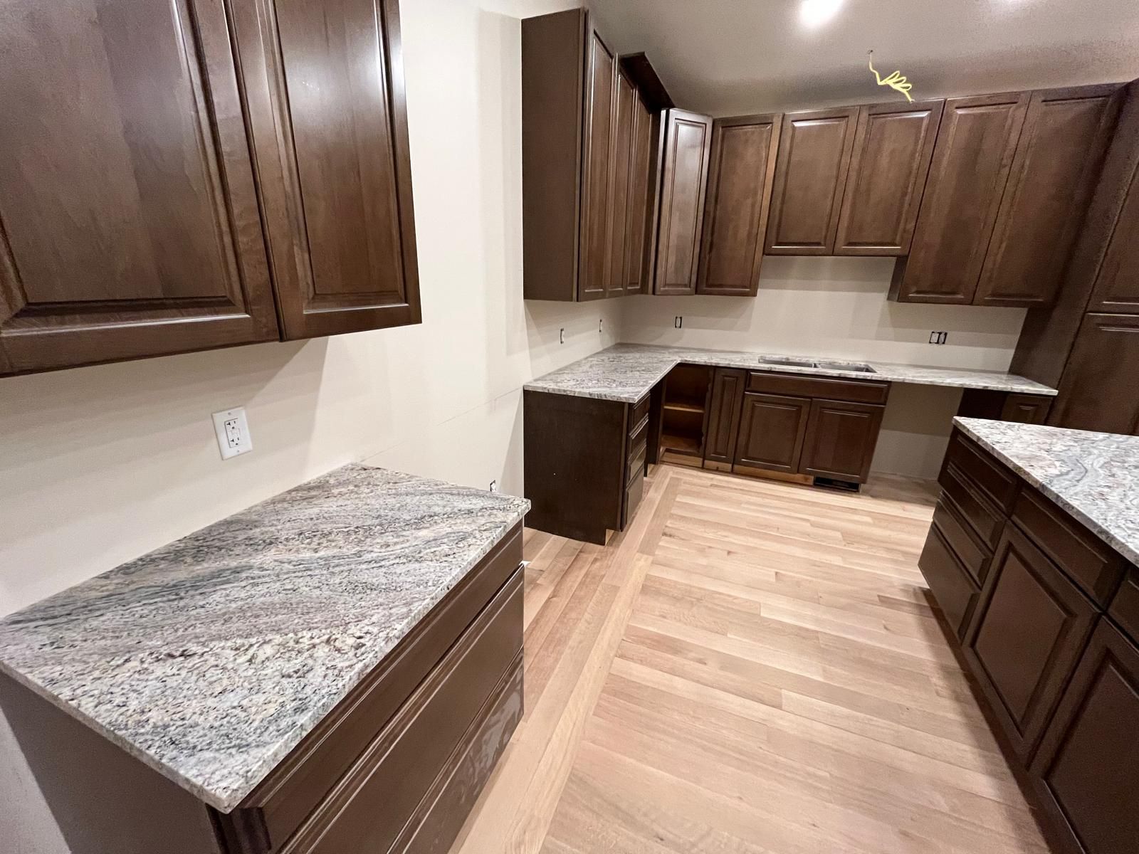 Kitchen with dark brown cabinets, light countertops, and light wooden floors.