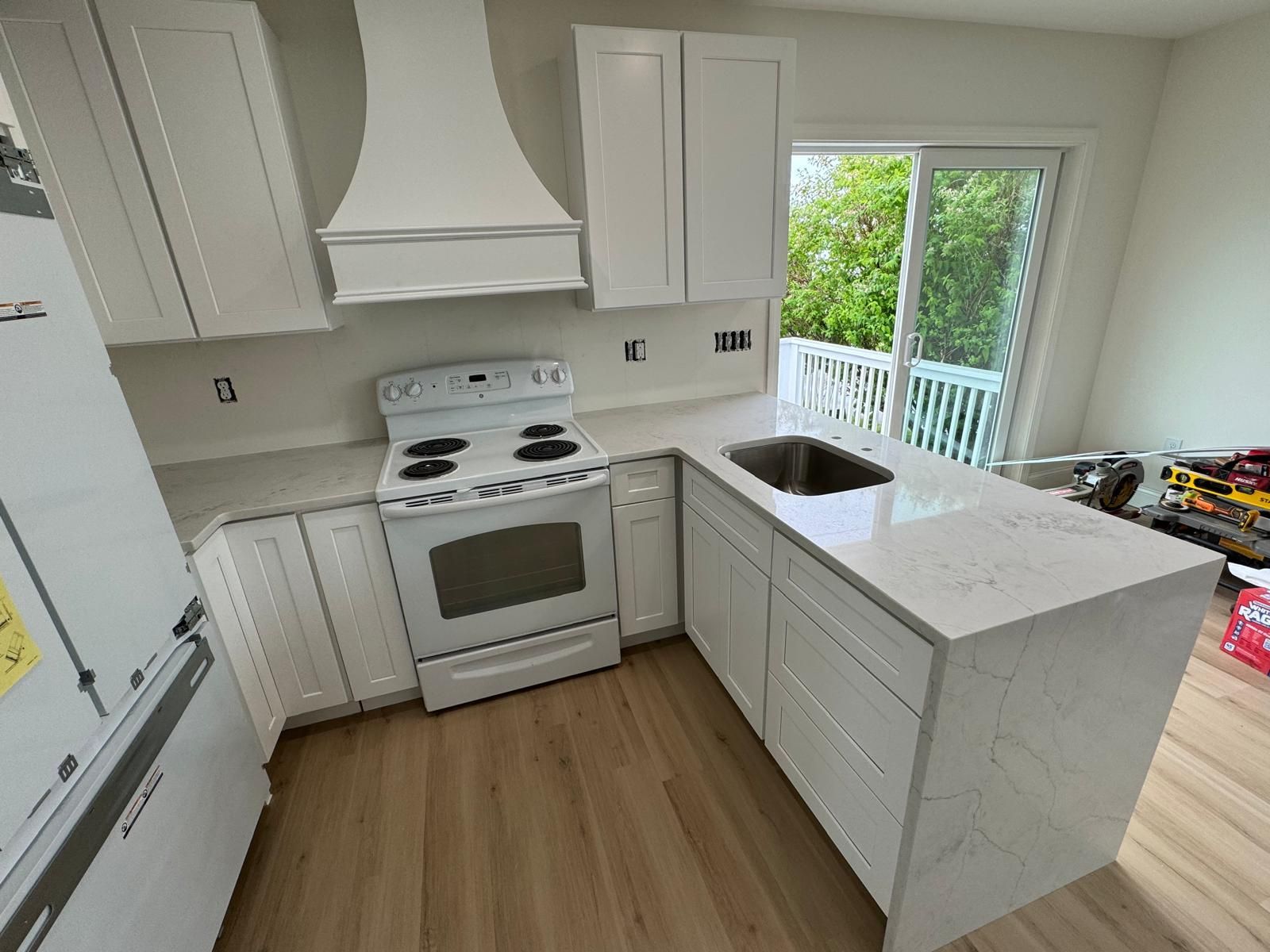 White kitchen with countertops, cabinets, appliances, and a sliding glass door.
