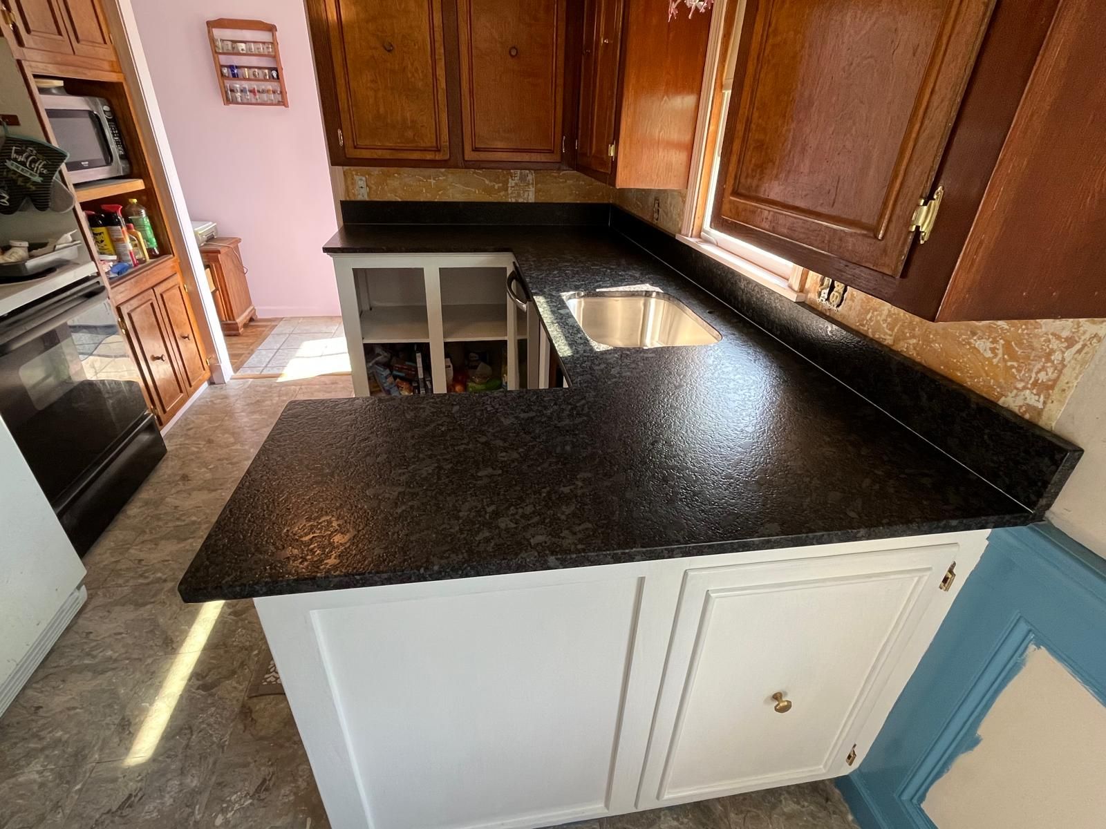 Kitchen with dark countertop, white cabinets, and dark wood upper cabinets.