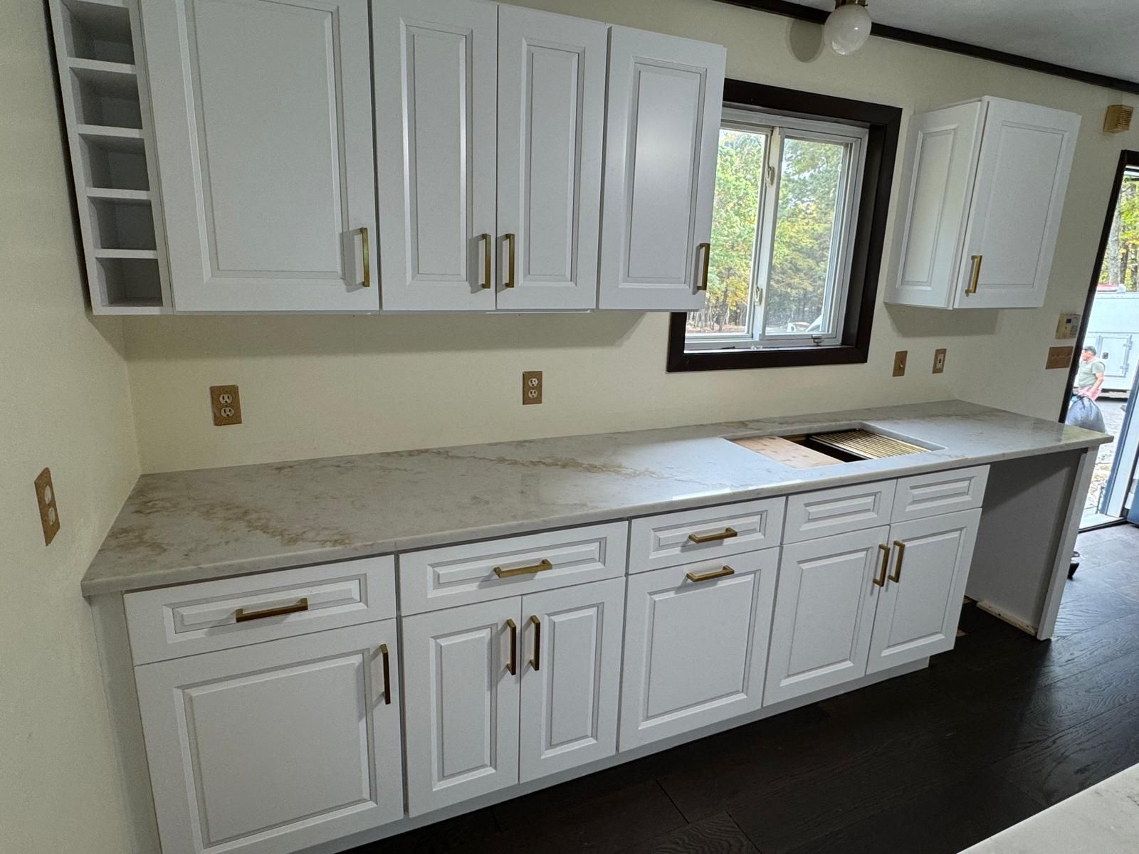 White kitchen cabinets with light countertops and a small window.