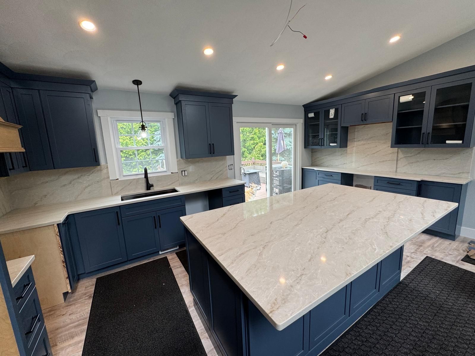 Newly renovated kitchen with navy blue cabinets, white countertops, and a large island.