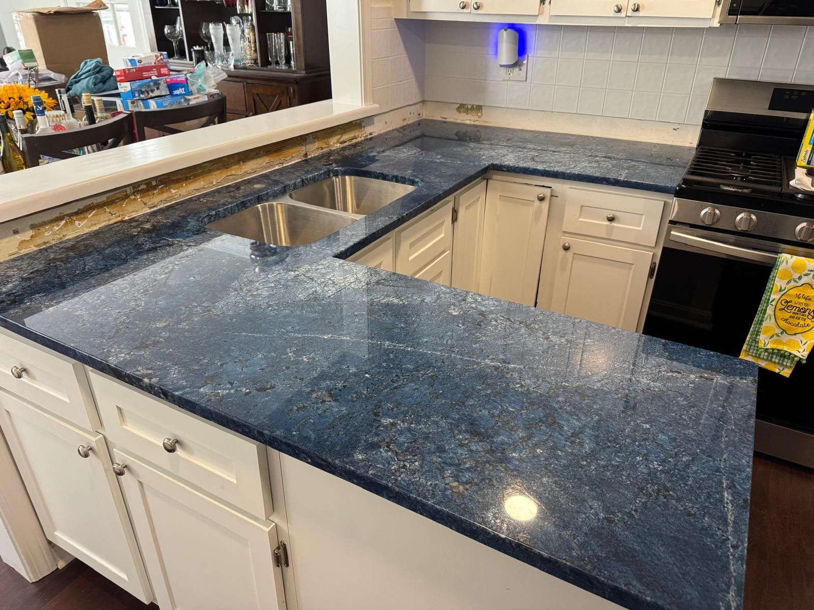 Blue speckled countertop with a double sink, white cabinets, and a stove.