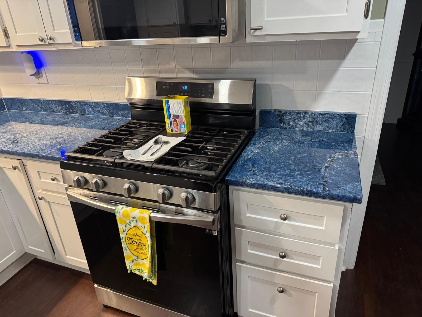Kitchen with white cabinets, blue countertops, and a stainless steel gas range.