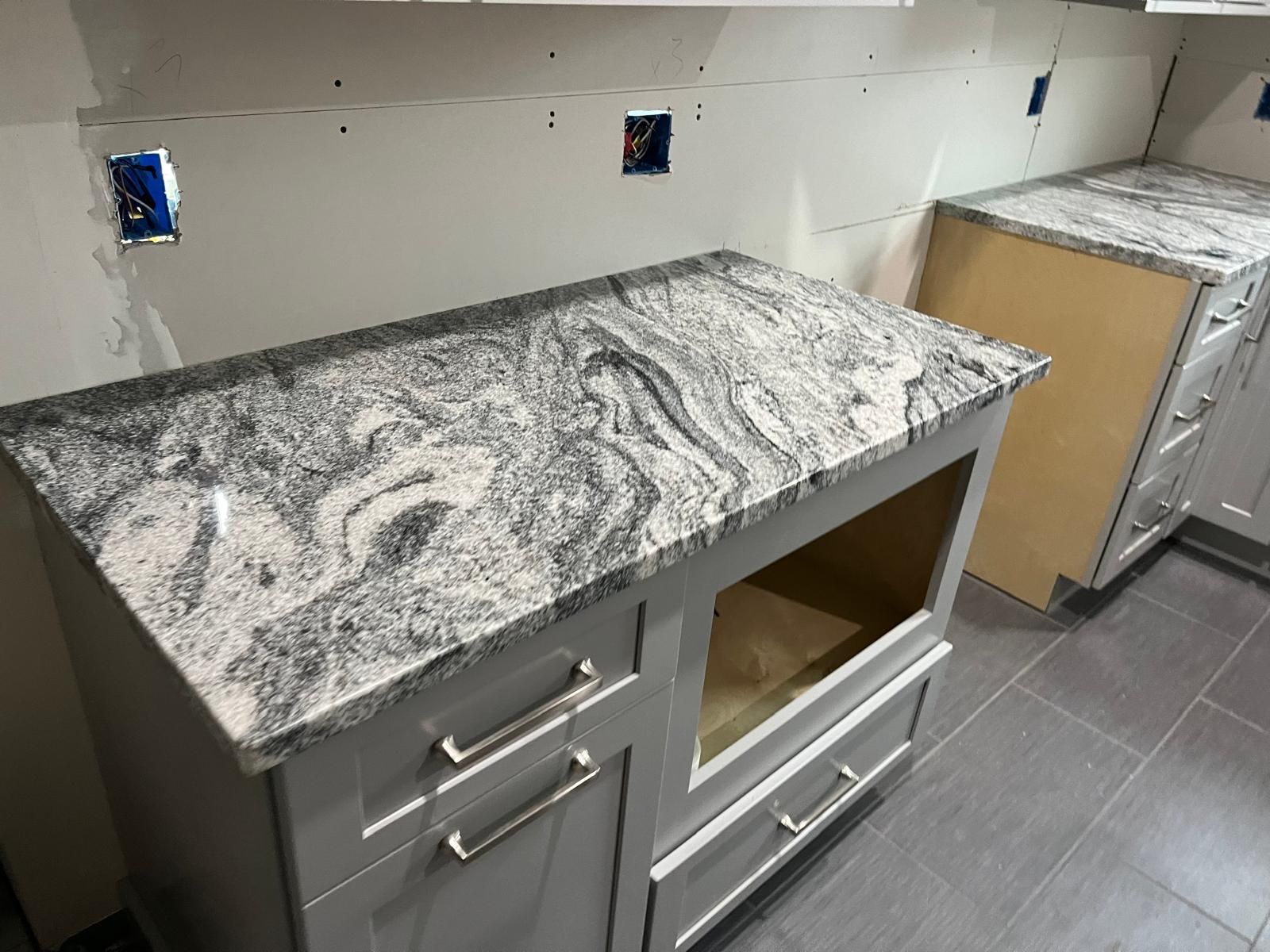 Kitchen remodel: grey cabinets with granite countertop, drywall, and partially tiled floor.