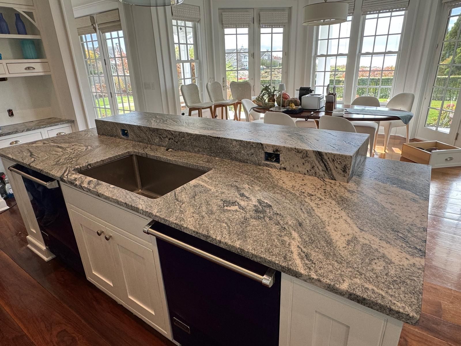 Kitchen island with granite countertop, sink, and dishwasher