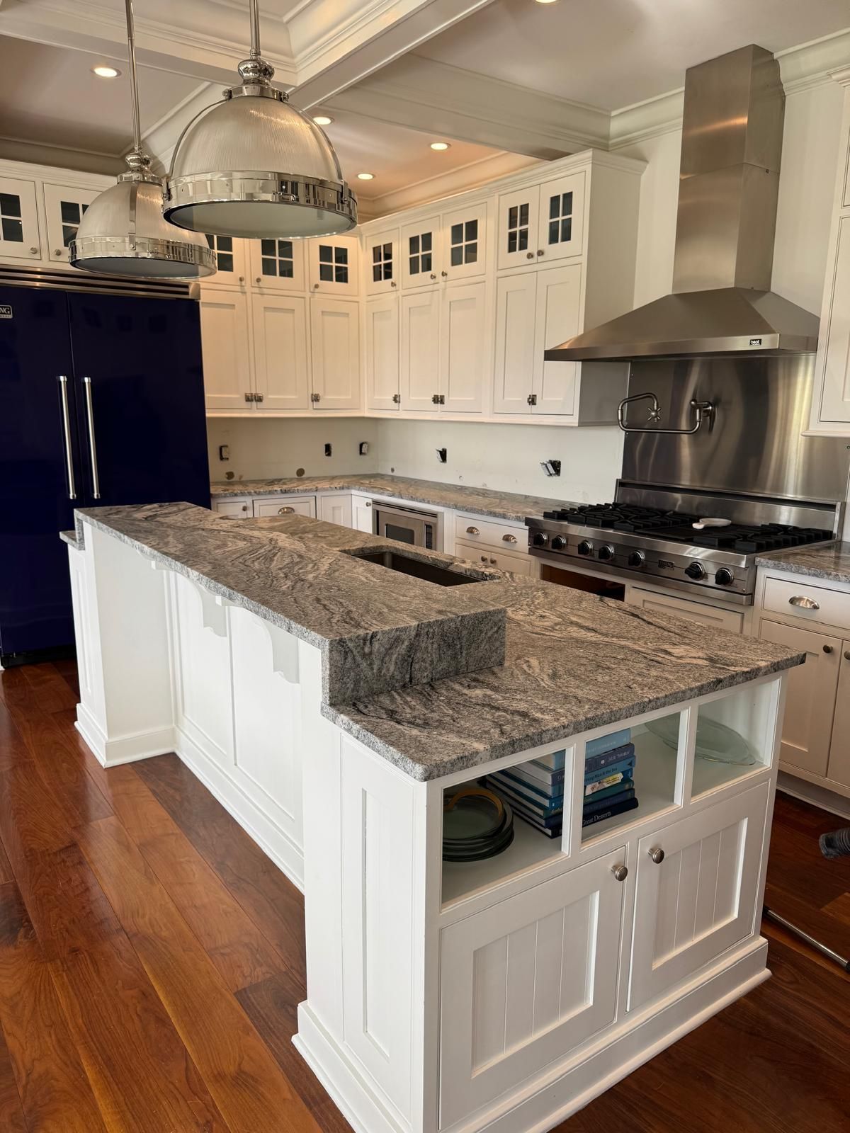 White kitchen with island, granite countertops, and stainless steel appliances.