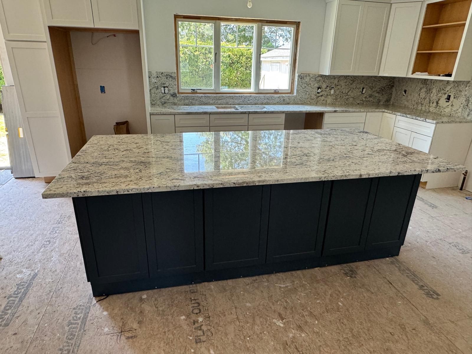 Kitchen island with dark blue cabinets and light granite countertop.