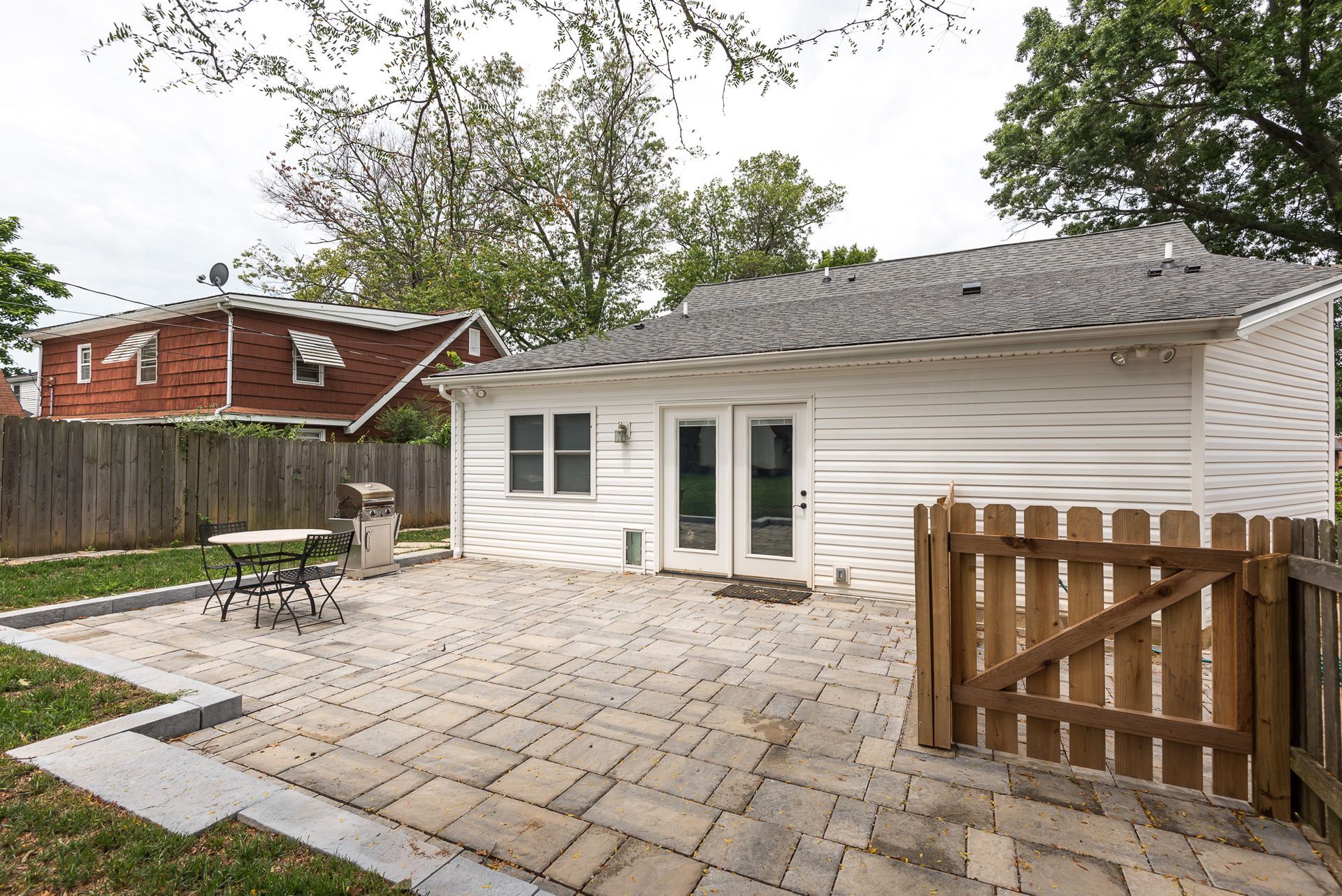 A white house with a brick patio and a wooden fence