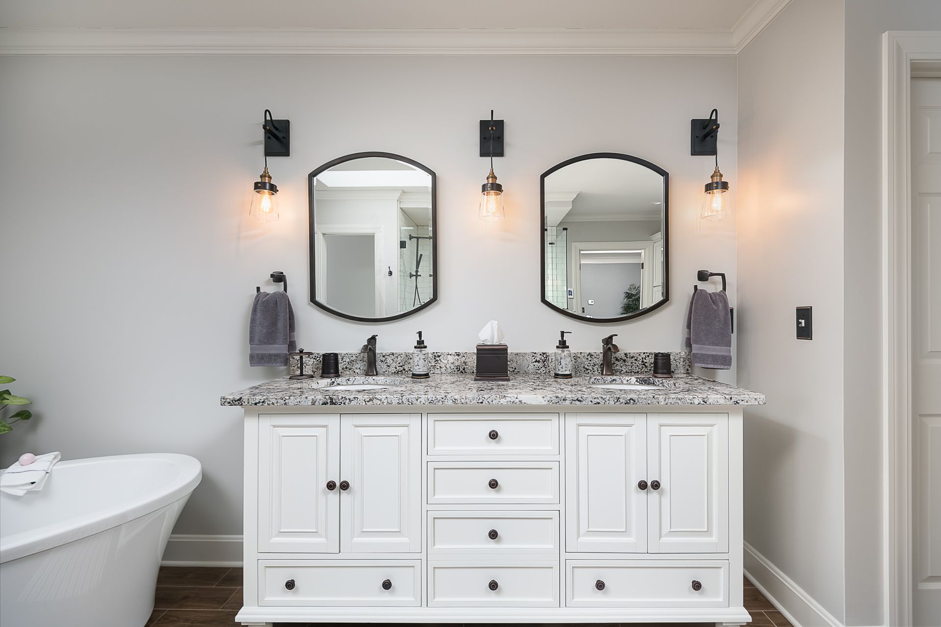 A bathroom with two sinks , two mirrors and a bathtub.
