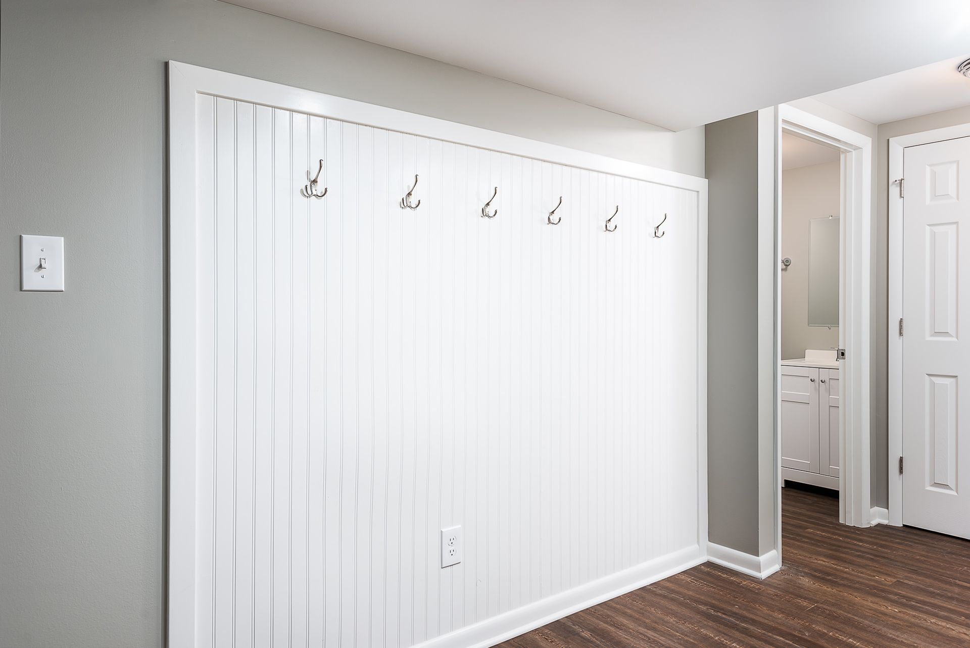 A white wall with hooks on it in a room.