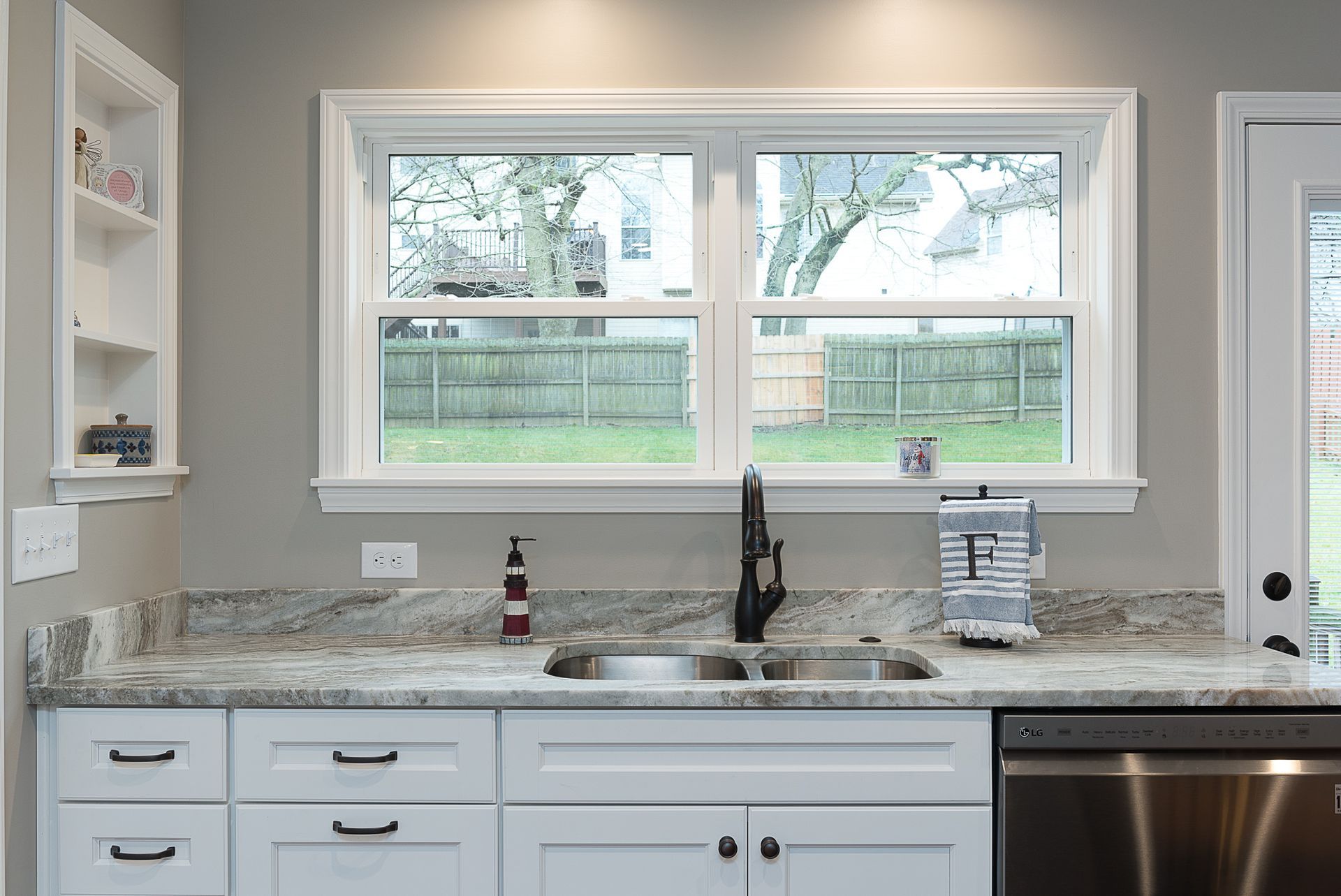 A kitchen with a sink , dishwasher , and two windows.