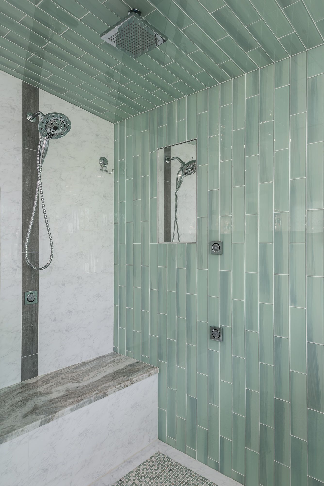 A bathroom with green tiles and a walk in shower.