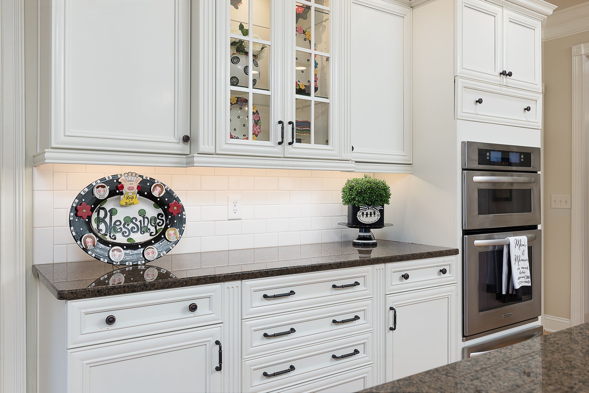 A kitchen with white cabinets , granite counter tops , and stainless steel appliances.