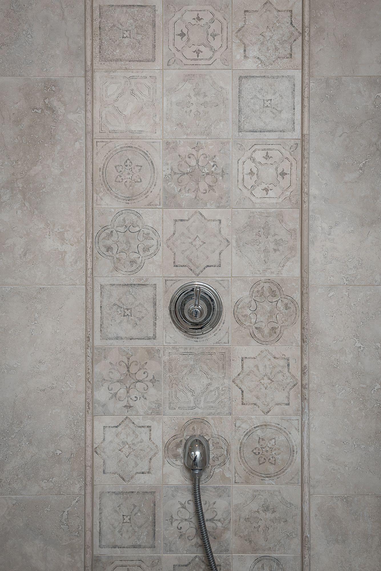 A close up of a shower head on a tiled wall.