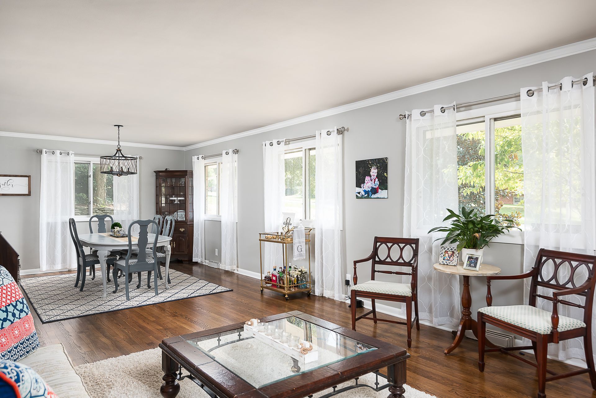 A living room with a glass coffee table , chairs , and a dining room table.