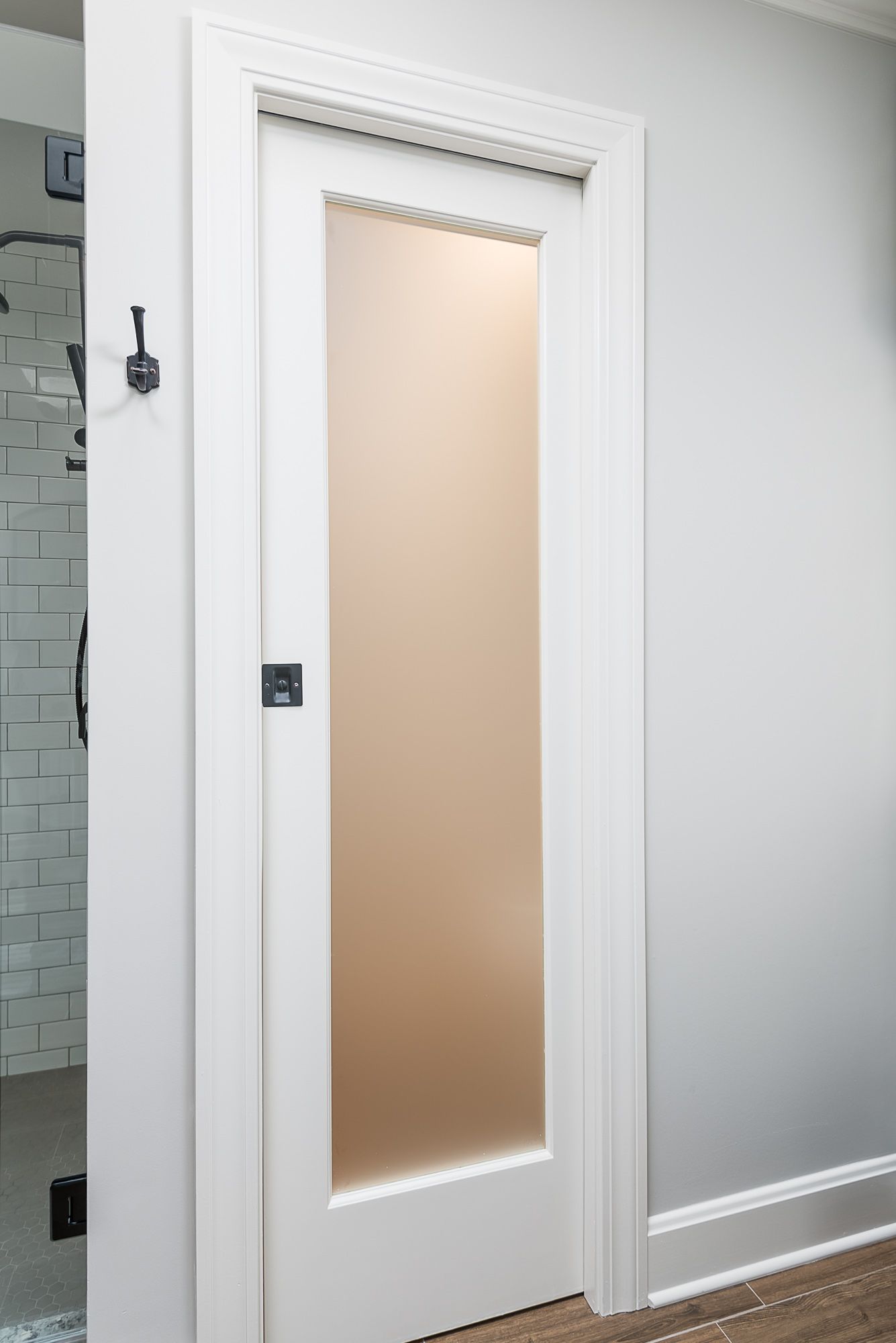 A white door with a frosted glass window in a bathroom.