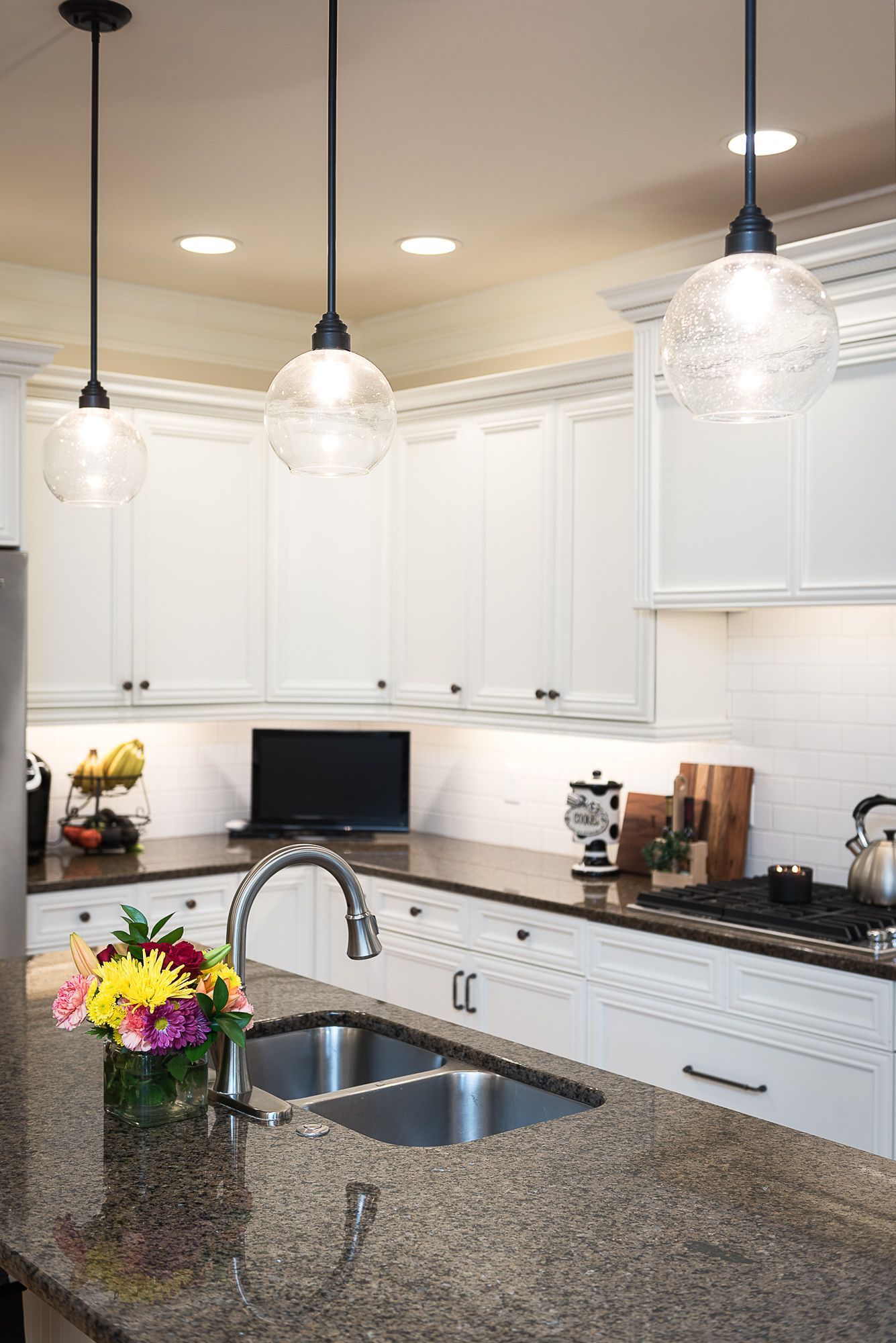 A kitchen with white cabinets , granite counter tops , stainless steel appliances and a sink.