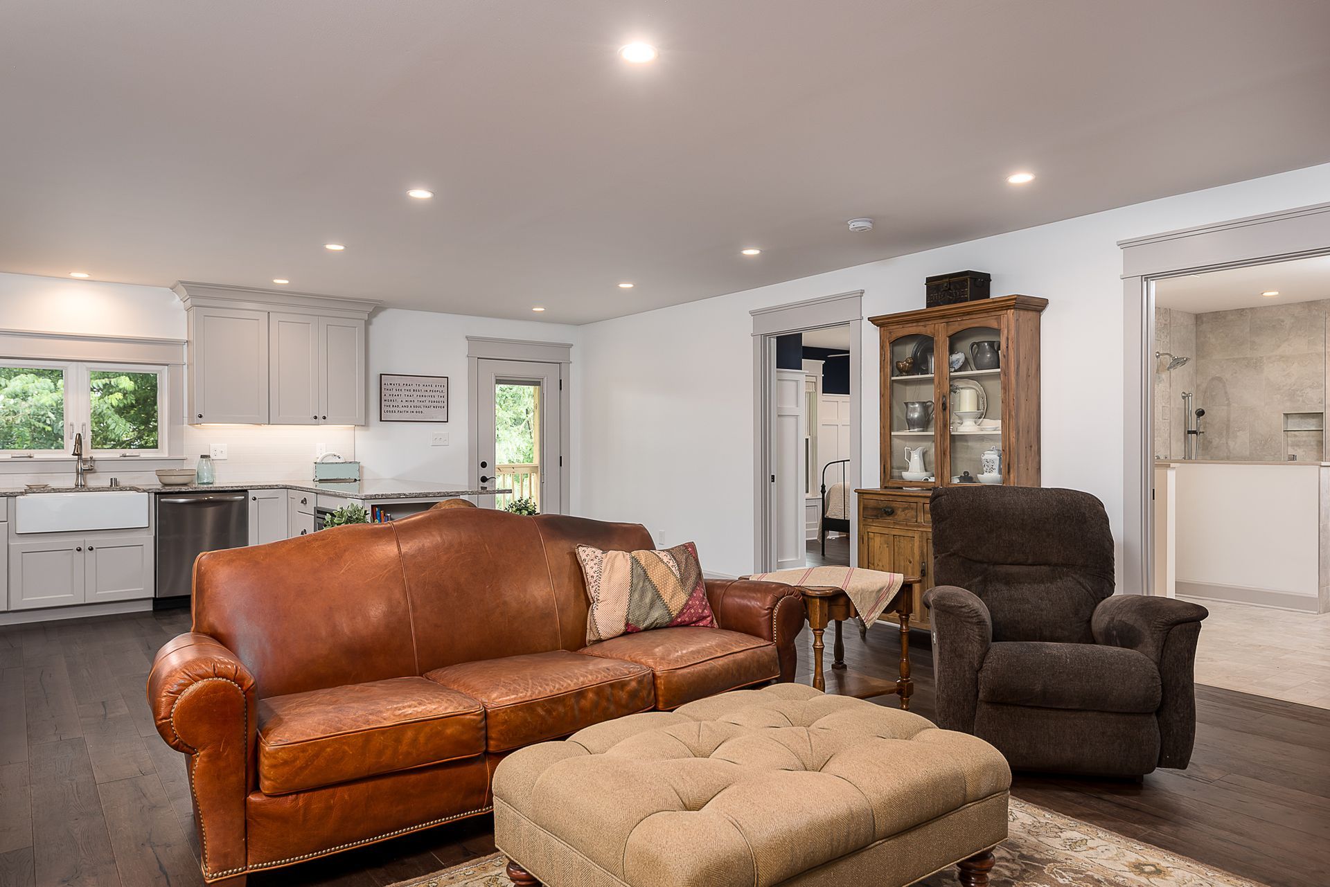 A living room with a couch , chair , ottoman and table.
